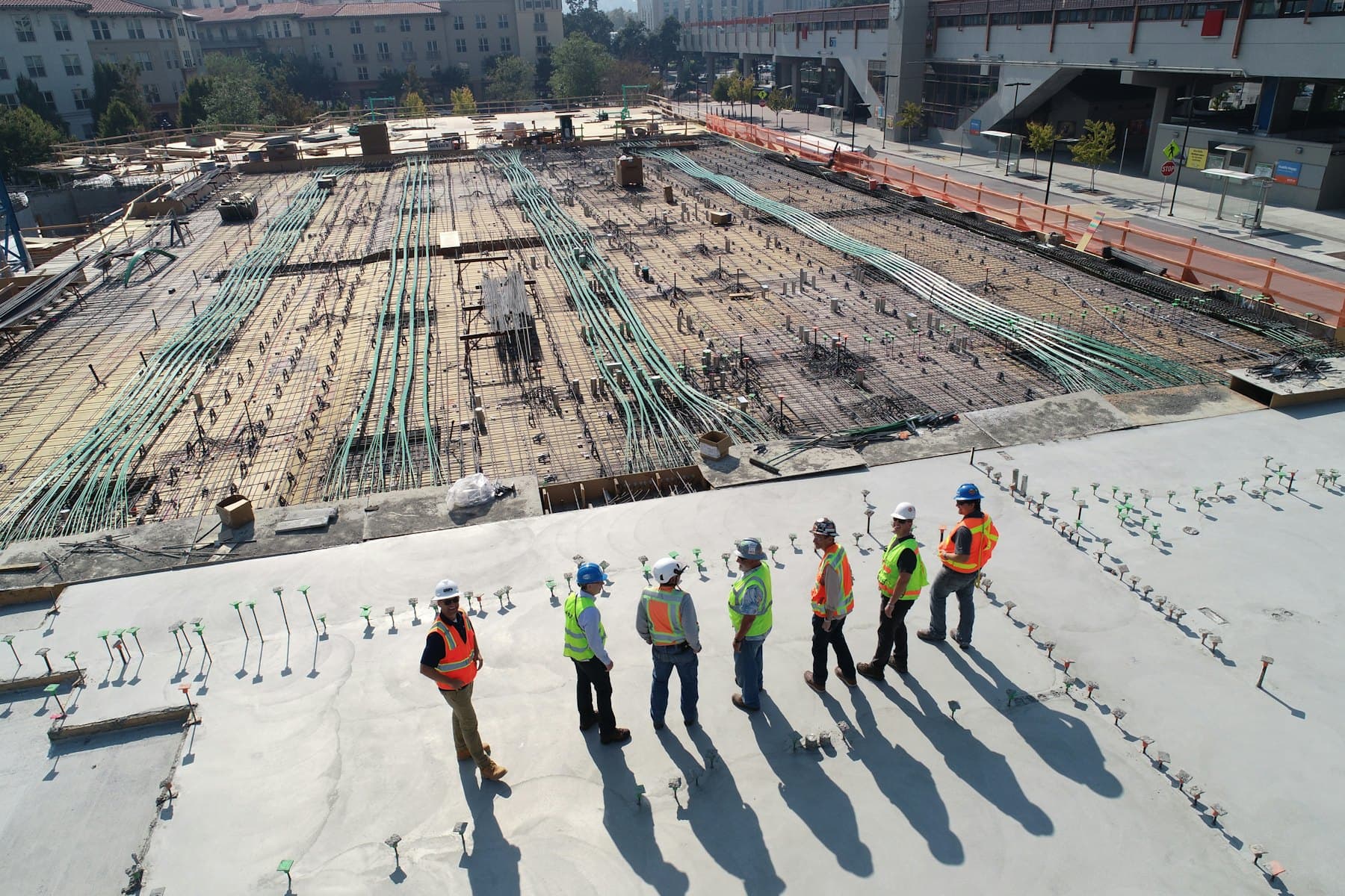 Vista aérea de um canteiro de obras com a equipe de engenharia analisando a armação da laje